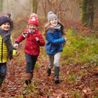 Tre børn løber i efterårsskov