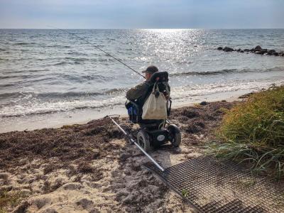 Person med handicap fisker fra stranden