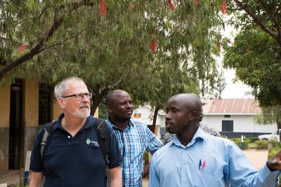 På billedet ses Friluftsrådets formand, Lars Mortensen. Han bliver vist rundt på en skole i Uganda af to mænd. Direktør for Friluftsrådet, Jan Ejlsted, går i bagved. 