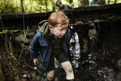 Dreng leger i mudder i skov