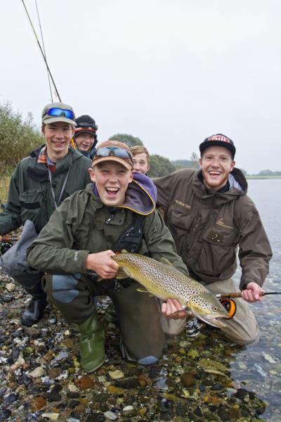 På billedet ses en flok glade drenge, der har fanget en stor fisk, som de stolte holder frem