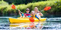 foto af gul kano med mor og to børn på en å