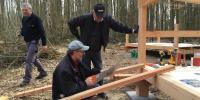 Frivillig bygger shelter i skoven 
