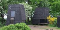 På billedet ses to nydesignede shelters i en skov. 