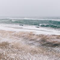 Bølger går højt op på strandens bred. Man kan fornemme, at der er meget vind