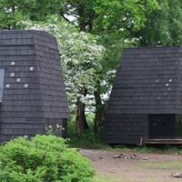 På billedet ses to nydesignede shelters i en skov. 